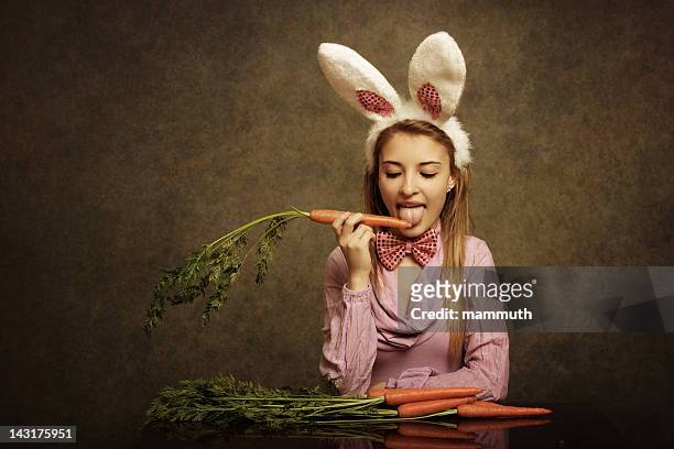 bunny girl licking a carrot - bunny girl stockfoto's en -beelden