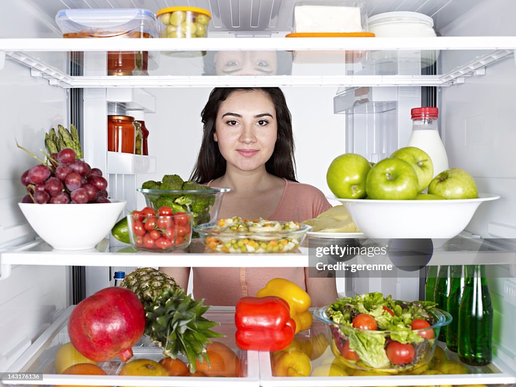 Looking from inside of a fridge to a young woman