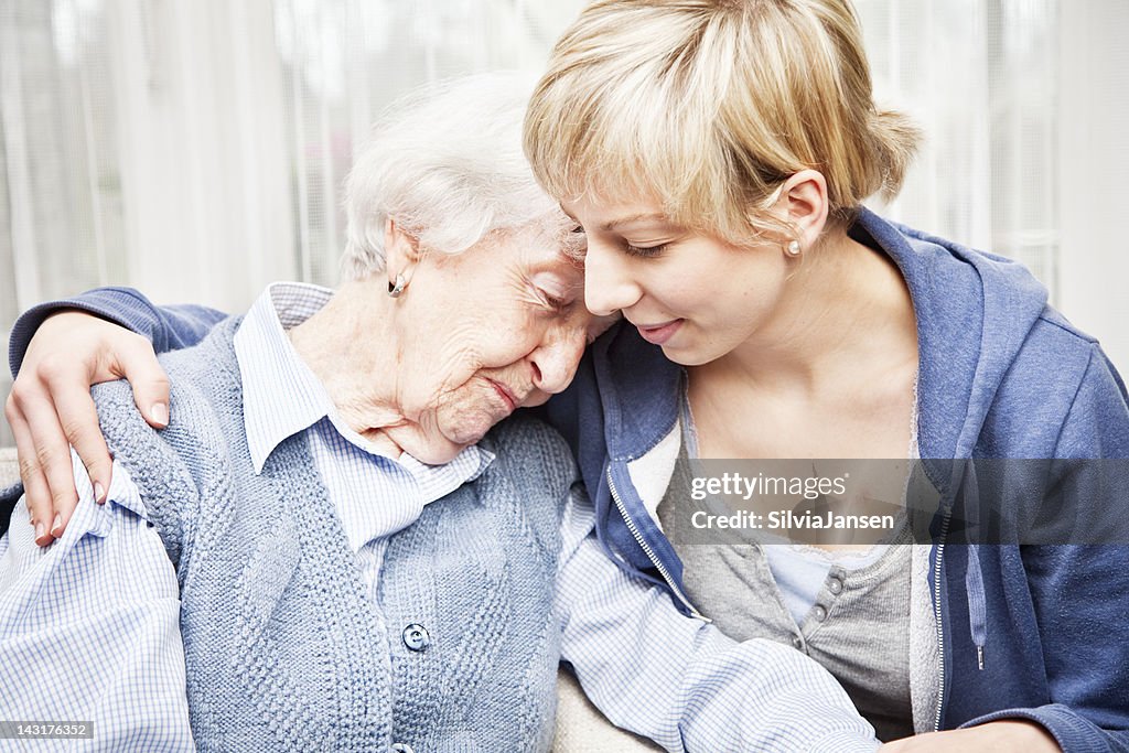 Home caregiver consoling sad senior woman