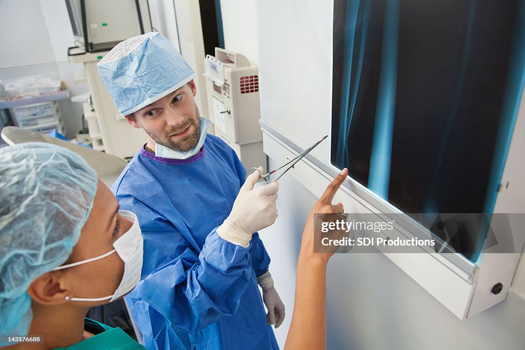 Surgeon and nurse discussing x-ray of broken bone