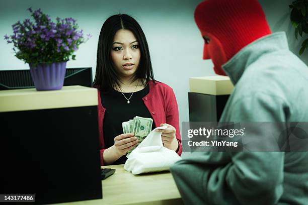 criminal robber robbing an asian retail bank teller at counter - bank robber stock pictures, royalty-free photos & images