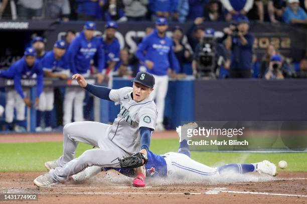 Santiago Espinal of the Toronto Blue Jays slides safe at home against Paul Sewald of the Seattle Mariners to score a run off of Vladimir Guerrero Jr....