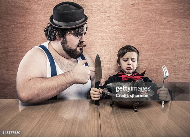 man encourages young sailor boy to eat raw fish heads - man fedora room stock pictures, royalty-free photos & images