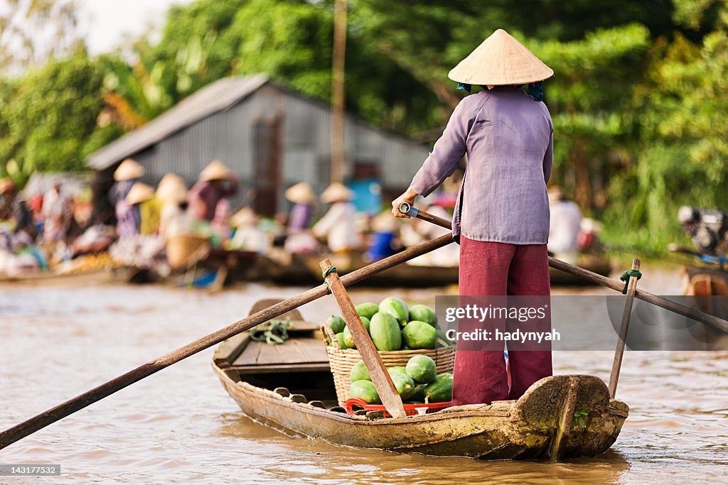 Vietnamese woman rowing  boat in the Mekong River Delta, Vietnam