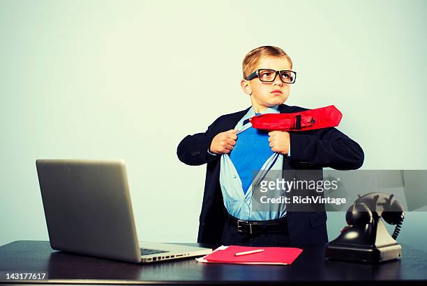 boy in office dressed as superhero at laptop - bureau de change stockfoto's en -beelden