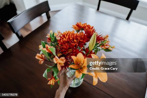 woman places flowers on dining table - lily bouquet stock pictures, royalty-free photos & images