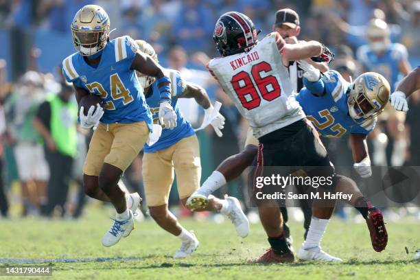 Jaylin Davies of the UCLA Bruins eludes the tackle of Dalton Kincaid of the Utah Utes after a fumble recovery during the second half of a game at the...