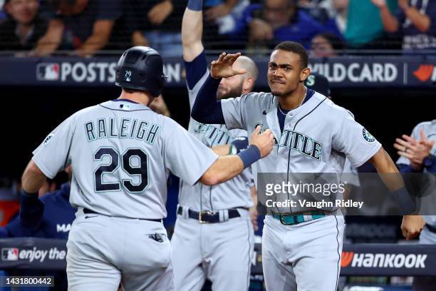 Cal Raleigh of the Seattle Mariners celebrates with Julio Rodriguez after scoring the go ahead run by a double hit by Adam Frazier against the...
