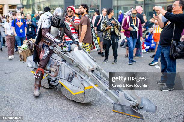 Cosplayer dressed as the Mandalorian poses with a Grogu doll hanging in his bag during New York Comic Con 2022 on October 08, 2022 in New York City.