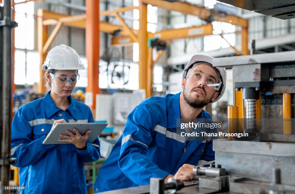 Female Machinery Engineer and male technical in safety protective wear while discuss with using tablet computer