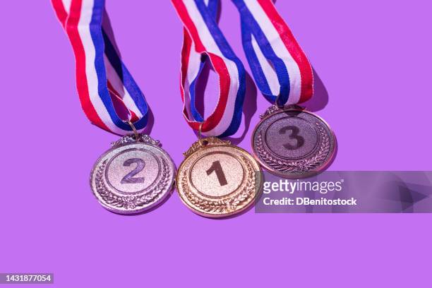 gold, silver and bronze medal, with the numbers 1, 2 and 3, on a purple background. concept of winner, olympic podium, medals, honor, women's day, winning woman, working woman and sports competition. - silver medal with ribbon stock pictures, royalty-free photos & images
