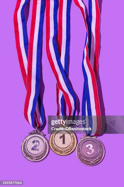 gold, silver and bronze medal, with the numbers 1, 2 and 3, on a purple background. concept of winner, olympic podium, medals, honor, women's day, winning woman, working woman and sports competition. - olympic ceremony stock pictures, royalty-free photos & images