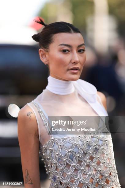 Fashion Week Guest seen wearing a glitter shiny dress, a white ribbon, black belt, white Miu Miu ballerinas, grey socks and a black Miu Miu handbag,...