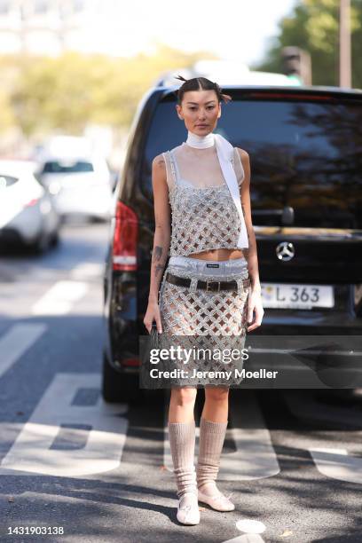 Fashion Week Guest seen wearing a glitter shiny dress, a white ribbon, black belt, white Miu Miu ballerinas, grey socks and a black Miu Miu handbag,...
