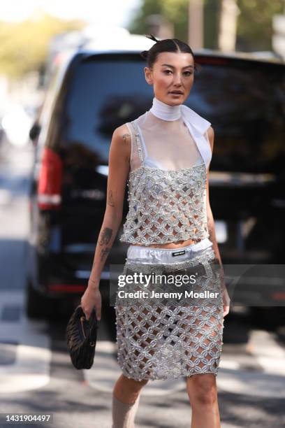 Fashion Week Guest seen wearing a glitter shiny dress, a white ribbon, black belt, white Miu Miu ballerinas, grey socks and a black Miu Miu handbag,...