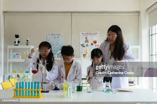 female science teacher  explains experiment to her students - children in a lab stock pictures, royalty-free photos & images