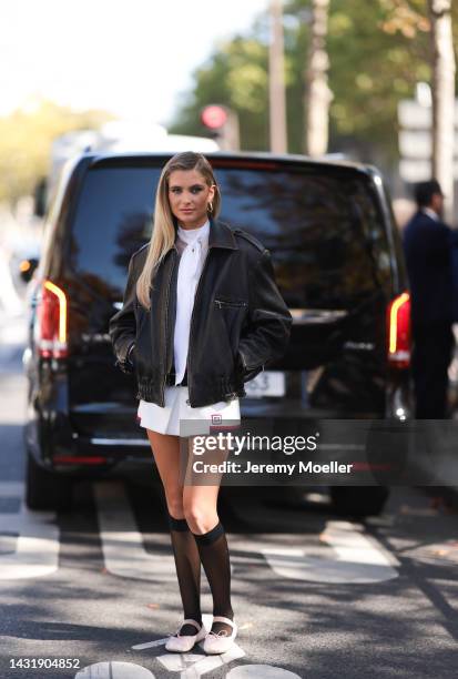 Xenia Adonts seen wearing a full Miu Miu look, brown leather jacket, white shirt and short skirt and black socks and rose ballerinas, outside Miu Miu...