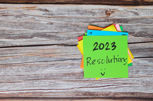 New year 2023 goals, resolutions and bucket list concept. Colorful sticky notes on wood background.