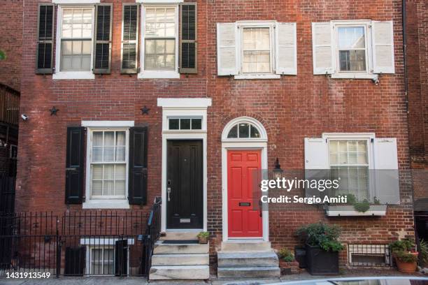 red brick terraced townhouses with black and red doors - philadelphia townhouse homes stockfoto's en -beelden