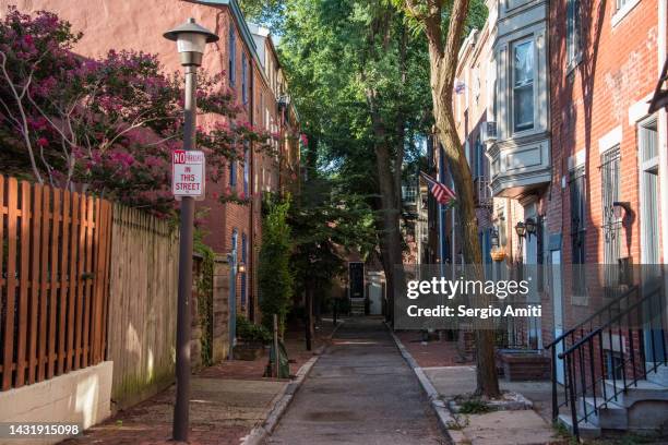 terraced brick townhouses with front stoops and american flag - philadelphia apartment townhouses stock pictures, royalty-free photos & images