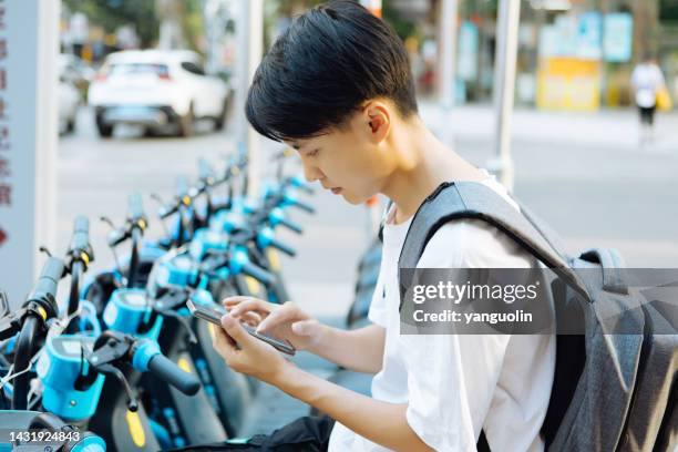 a man rides an electric bike down the street and starts scanning the code to navigate -- sustainable lifestyle - compass city stockfoto's en -beelden