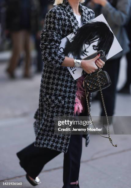 Fashion week guest seen wearing a long grey and black coat and a chanel leather bag, outside Chanel during Paris Fashion Week on October 04, 2022 in...