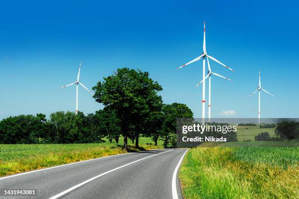 wind turbines on green field against blue sky - the whirligig stockfoto's en -beelden