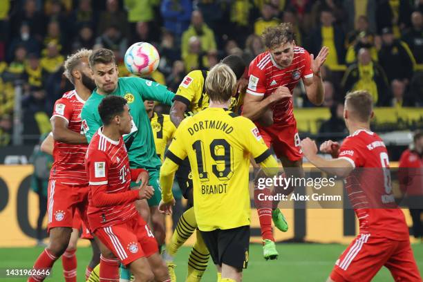 Leon Goretzka of Bayern Muenchen clears the ball whilst under pressure from goalkeeper Alexander Meyer and Anthony Modeste of Borussia Dortmund...