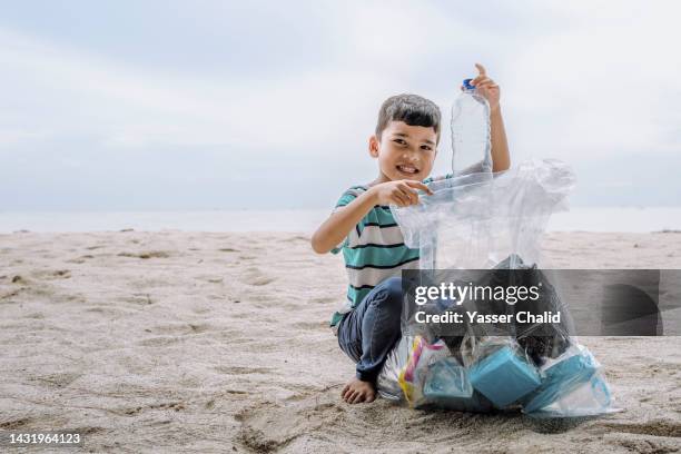 portrait of a little boy cleaning up a beach - picking up garbage stock pictures, royalty-free photos & images