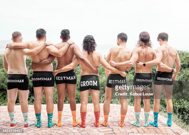 bachelor party, men underwear and groomsmen standing shirtless outside for fun, celebration and support for groom on his wedding day. colorful socks, friend group and standing together from behind - 男性告別單身派對 個照片及圖片檔