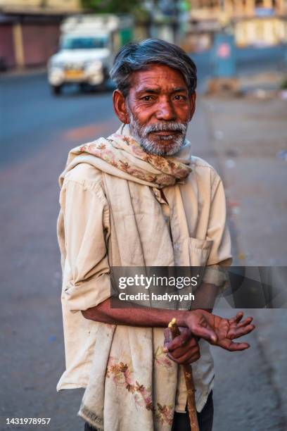 homeless man standing on a street and asking for help - aalmoes stockfoto's en -beelden