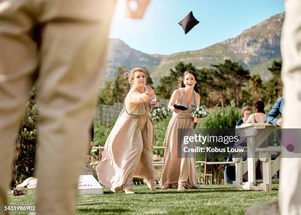 mariage, amis et jeu avec les femmes rire et jouer au lancer de sac de haricots lors d’une cérémonie en plein air. famille, fête et demoiselles d’honneur se liant et profitant du divertissement des invités avec une activité amusante lors d’un é - réception de mariage photos et images de collection