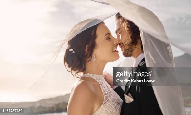 wedding, love and couple kiss with veil in nature after ceremony celebration, event and party together. happy, marriage and hug with man and woman at outdoor lake venue for romance, smile and union - wedding after party stock pictures, royalty-free photos & images