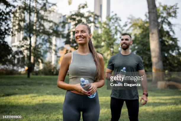 portrait of happy fit people drinking water and running together outdoors. couple sport healthy lifestyle - couple outdoors imagens e fotografias de stock