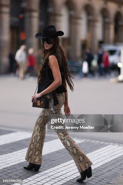 Sabina Jakubowicz seen wearing a Louis Vuitton petite malle bag, big shades by Gucci, Gucci animal print pants, a gold and black vest by Louis...