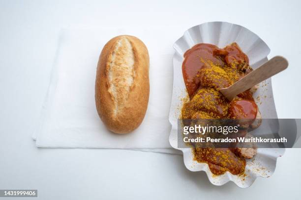 currywurst, grilled pork sausage on top with curry powder served with curry ketchup sauce on white paper plate. - restaurant düsseldorf stock pictures, royalty-free photos & images