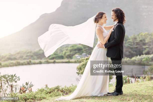 wedding, wind and a couple, veil waving in beautiful natural landscape. nature, love and a happy bride and groom standing in park together. luxury venue, man and woman at outdoor marriage ceremony. - blowing a kiss imagens e fotografias de stock