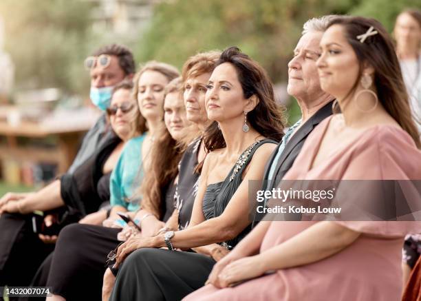 ospiti di nozze seduti in una folla di familiari e amici all'evento all'aperto. le persone si siedono alla cerimonia di matrimonio fuori nella natura in estate, celebrando il matrimonio. amore, supporto e pubblico felice - invitato a un matrimonio foto e immagini stock