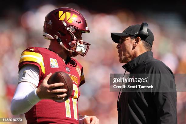 Carson Wentz of the Washington Commanders talks with head coach Ron Rivera during the first half against the Tennessee Titans at FedExField on...