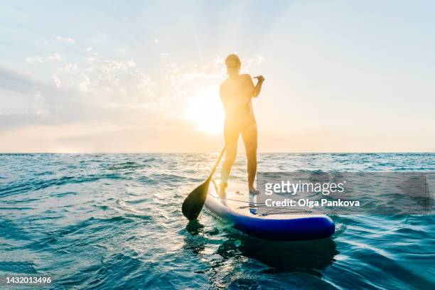 woman stands on a paddle board in the sea during sunset. - hot women on boats ストックフォトと画像