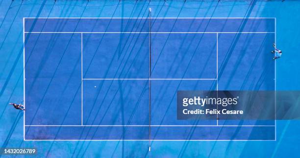 aerial view of two tennis players on a blue tennis court. - blue tennis racket stock pictures, royalty-free photos & images