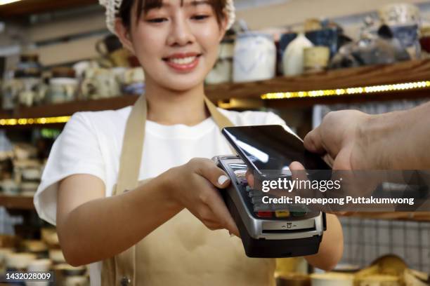 close up of a male's hand paying bill with credit card contactless payment on smartphone, scanning on a card machine. electronic payment. banking and technology - poes stock-fotos und bilder