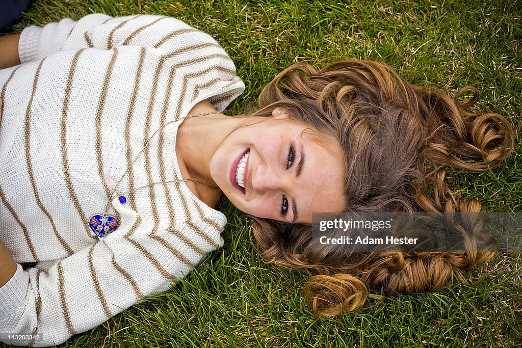 Portrait of a young girl lying outside in a park.