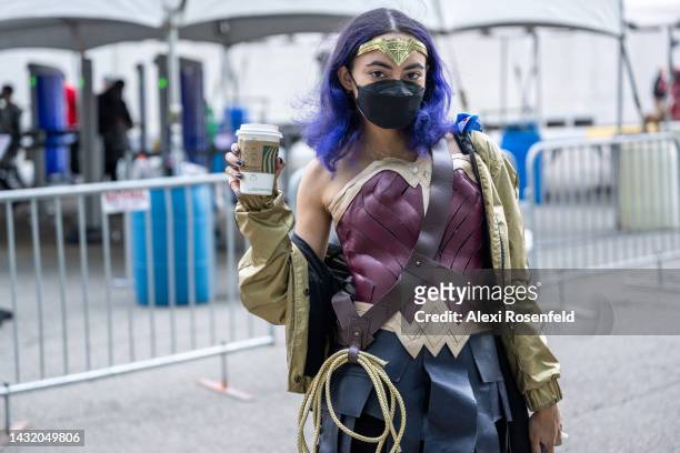 Person dressed as Wonder Woman poses with a Starbucks coffee at New York Comic Con 2022 on October 09, 2022 in New York City. The four-day event,...