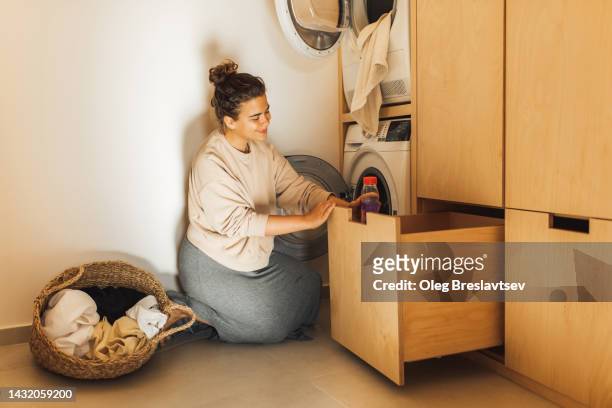 young housewife woman loading washing machine with laundry. housekeeping chores with pleasure. - placard fotografías e imágenes de stock