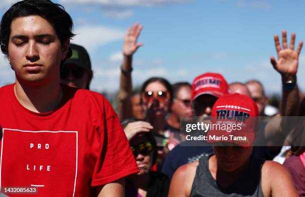 Attendees pray at a campaign rally attended by former U.S. President Donald Trump at Legacy Sports USA on October 09, 2022 in Mesa, Arizona. Trump...