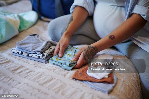 pregnant, woman and baby, clothes on bed with mother fold laundry in a bedroom for newborn. love, future and planning by excited lady choosing outfit for birth of child, preparation and hands closeup - baby clothes stock pictures, royalty-free photos & images