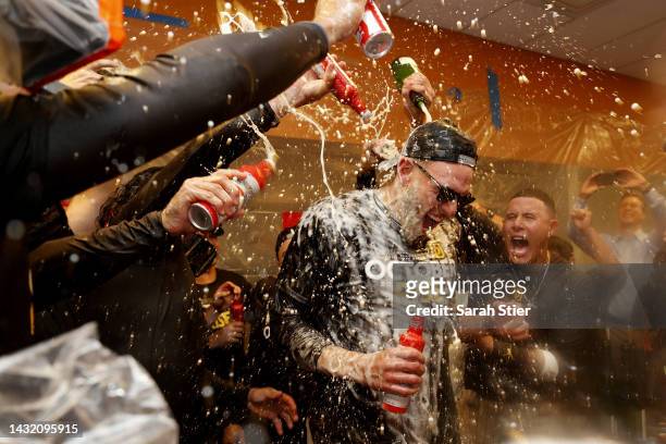 Joe Musgrove and Manny Machado of the San Diego Padres celebrate with their teammates in the locker room after defeating the New York Mets in game...