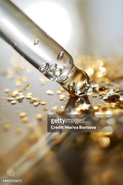a dropper with cosmetic gel on a background of sparkling gold sequins. - 血清樣本 個照片及圖片檔