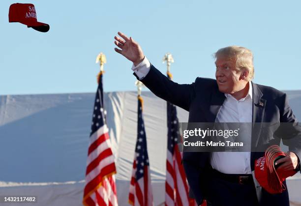 Former U.S. President Donald Trump tosses Save America hats to the crowd at a campaign rally at Legacy Sports USA on October 09, 2022 in Mesa,...